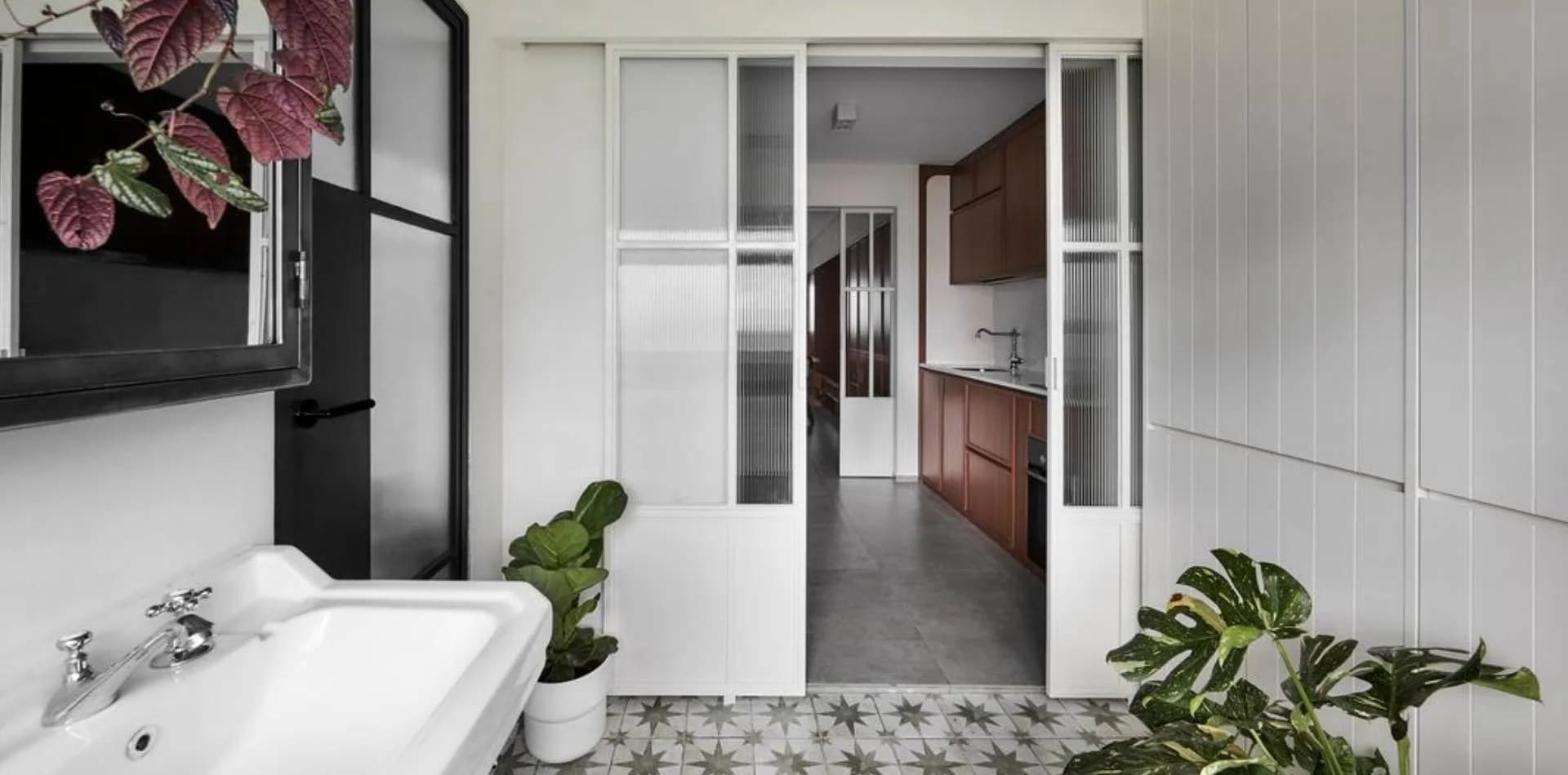 Fluted-glass sliding doors with a black frame between a bathroom and a kitchen