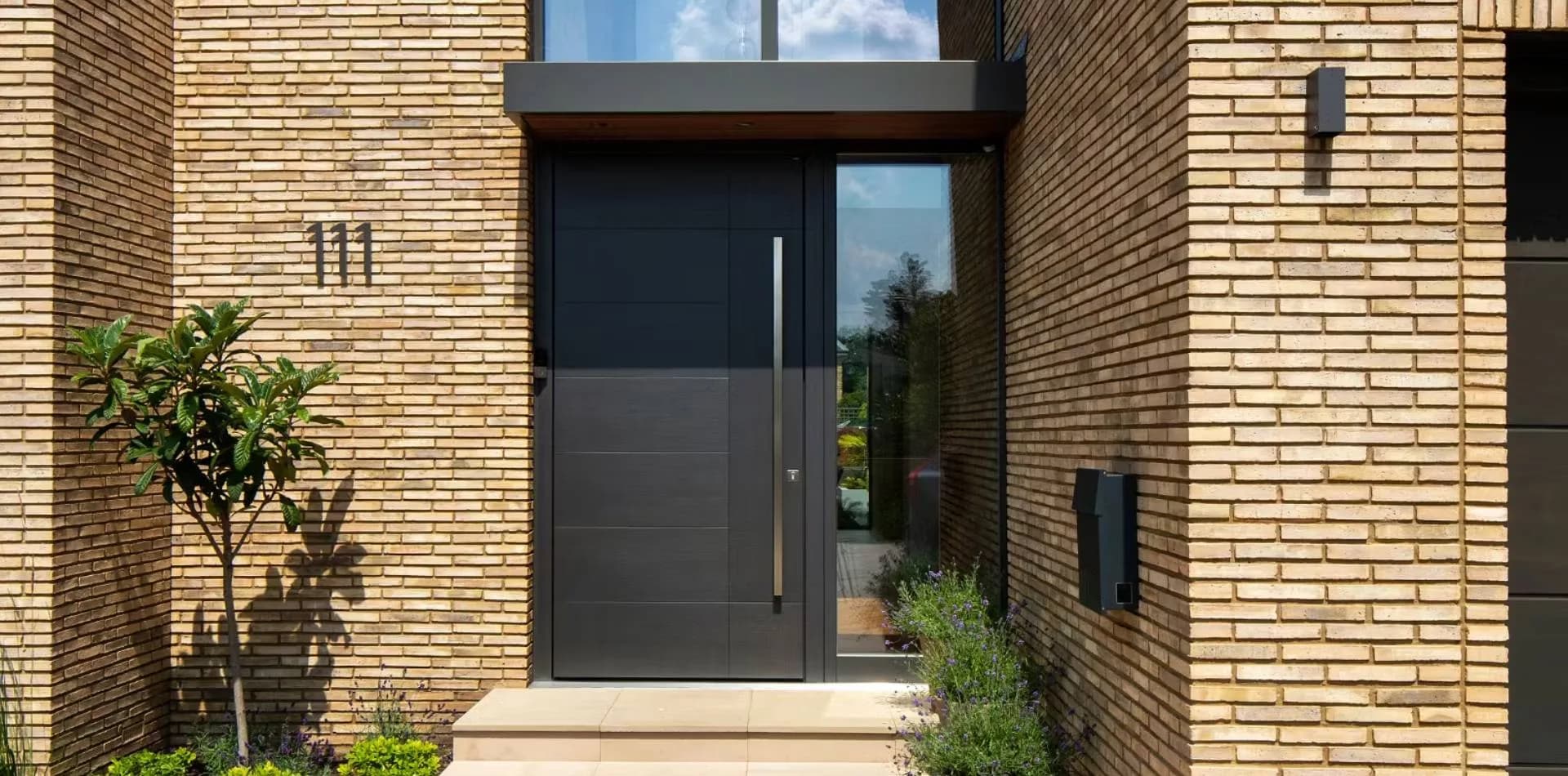 Black front door with a long handle set in a brick house