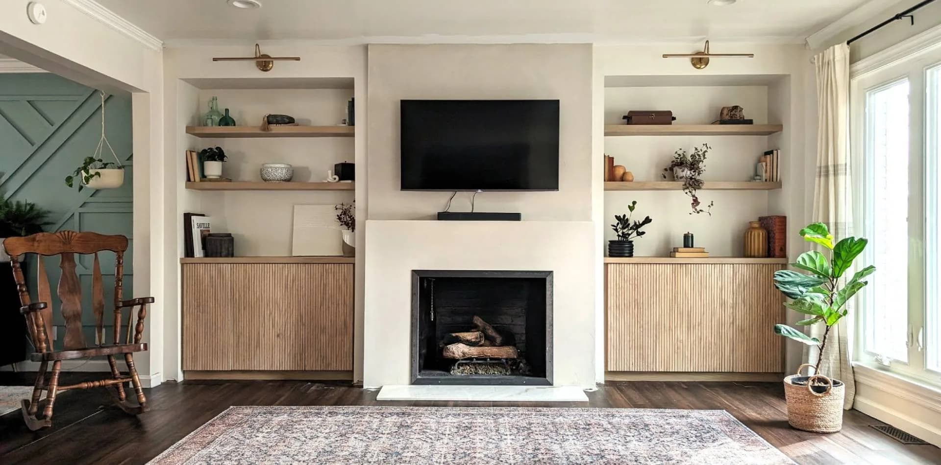 Built-in wood cabinets and shelving either side of a living-room fireplace
