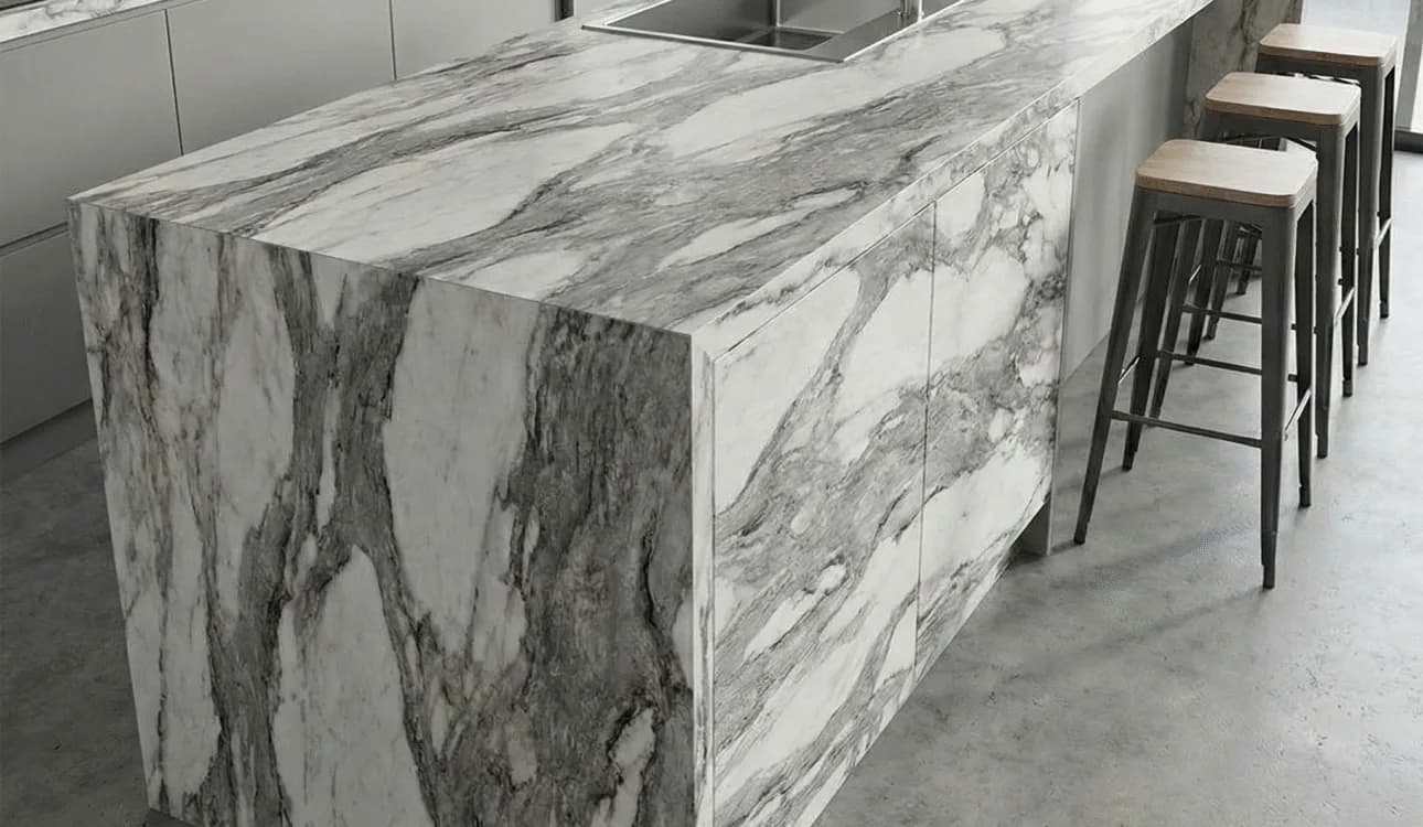 Kitchen island with a veined white marble-effect surface and bar stools