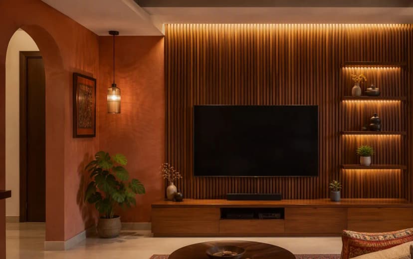 Bangalore living room TV wall with vertical fluted wood panels, backlit display niches and a terracotta limewash accent wall