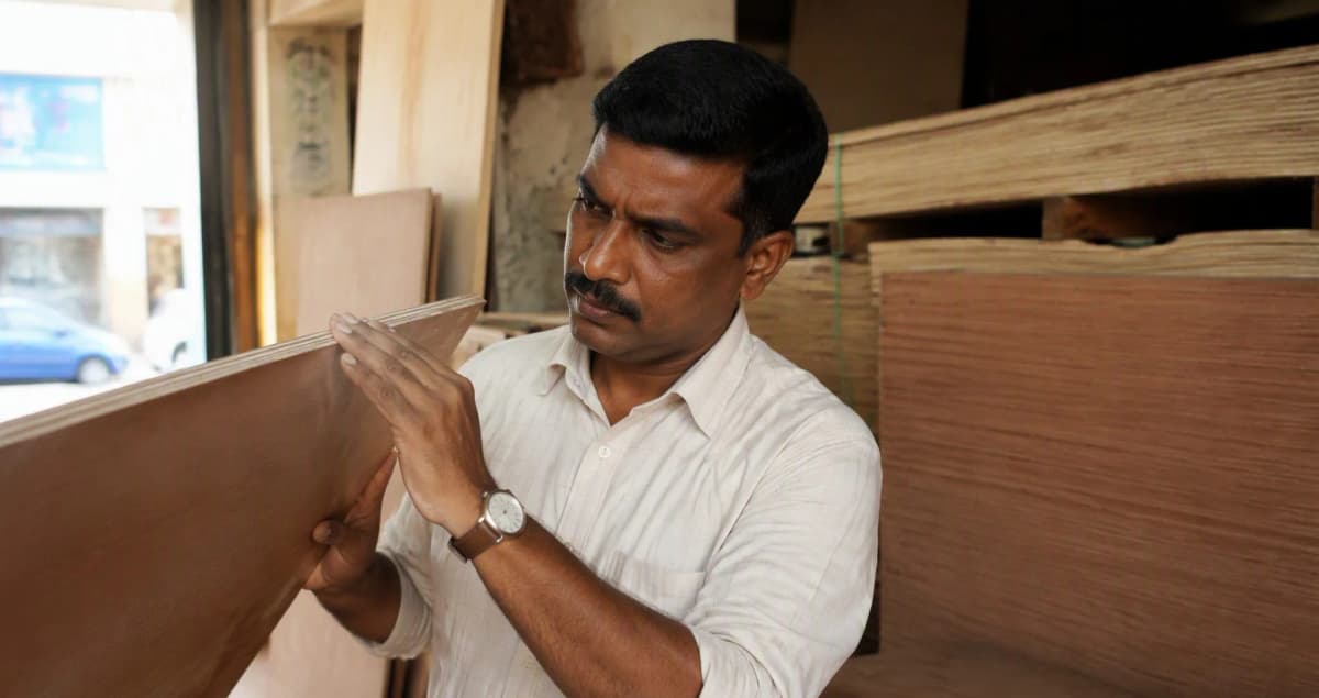 Homeowner inspecting the edge of a plywood sheet at an Indian plywood dealer shop