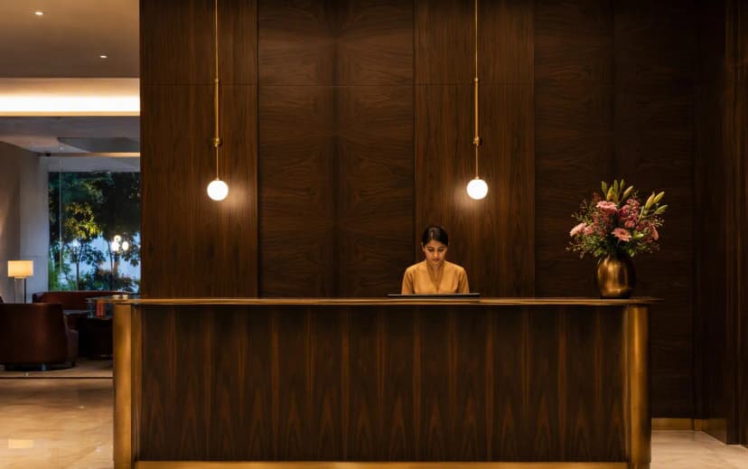 A boutique hotel reception desk with dark book-matched veneer panels and brass detailing