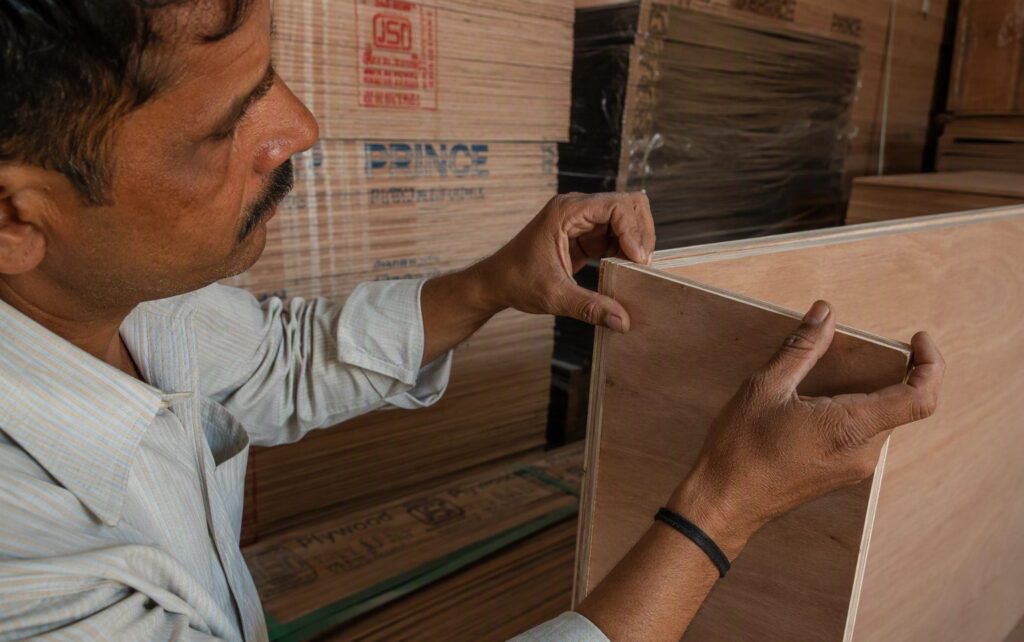 Carpenter inspecting the edge layers of a plywood sheet at a dealer shop